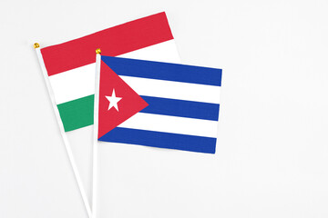 Cuba and Hungary stick flags on white background. High quality fabric, miniature national flag. Peaceful global concept.White floor for copy space.
