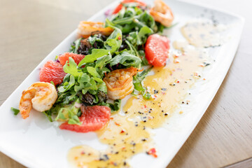 Delicious dish with grilled shrimps, slice grapefruit and arugula salad and spicy fried prawns. Restaurant menu, natural and organic food concept.