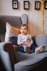 Fototapeta premium Cute baby girl sitting on big armchair and smile