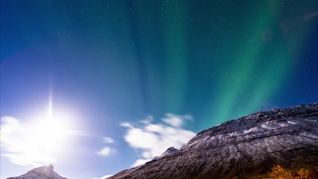 Night sky timelapse of a moonlit mountain and Aurora Borealis northern lights with stars in the arctic. Iceland, Westfjords
