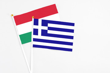 Greece and Hungary stick flags on white background. High quality fabric, miniature national flag. Peaceful global concept.White floor for copy space.