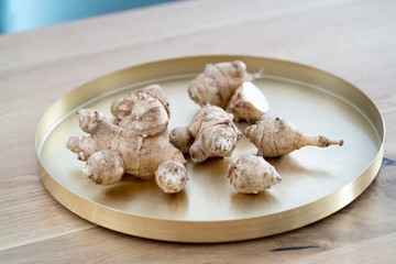 Root of topinabour lay on a gold tray. Jerusalem artichokes called sunroot.