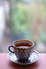 Tea in a vintage porcelain cup on stack of pastel colored books. Selective focus.