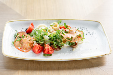 Fresh Salad with tomatoes, basil, mozzarella, and olive oil on wooden background. Italian traditional caprese salad. Mediterranean, natural and organic food concept.