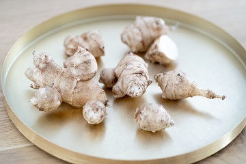 Root of topinabour lay on a gold tray. Jerusalem artichokes called sunroot.