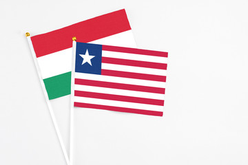 Liberia and Hungary stick flags on white background. High quality fabric, miniature national flag. Peaceful global concept.White floor for copy space.