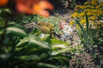 Dwarf statue between flowers and trees