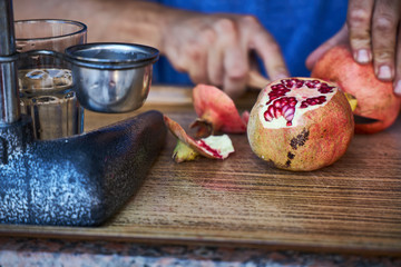 Street vendor peels ripe pomegranate for squeezing juice.