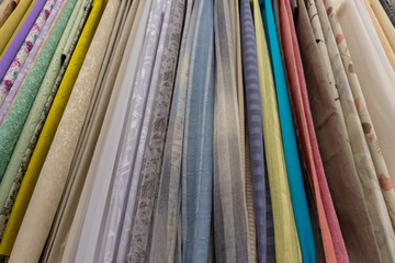 Fototapeta na wymiar fabrics hang on a counter in a fabric store. assortment of fabrics