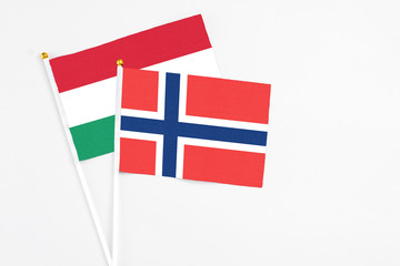 Obraz premium Norway and Hungary stick flags on white background. High quality fabric, miniature national flag. Peaceful global concept.White floor for copy space.