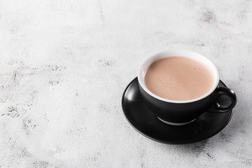 Cup of hot cocoa or hot chocolate in dark cup isolated on bright marble background. Advertising for cafe menu. Coffee shop menu. Horizontal photo. traditional drinks for winter time