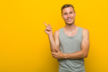 Young caucasian sport man smiling cheerfully pointing with forefinger away.