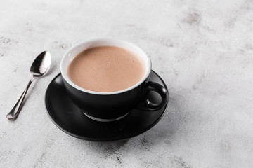 Cup of hot cocoa or hot chocolate in dark cup isolated on bright marble background. Advertising for cafe menu. Coffee shop menu. Horizontal photo. traditional drinks for winter time