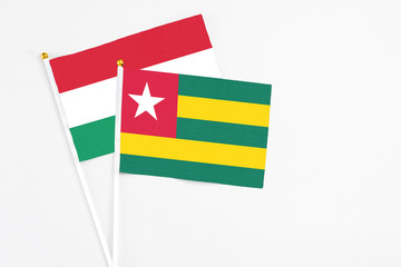 Togo and Hungary stick flags on white background. High quality fabric, miniature national flag. Peaceful global concept.White floor for copy space.