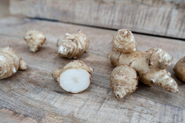 Root of topinabur on a wooden background. Jerusalem artichokes called sunroot.