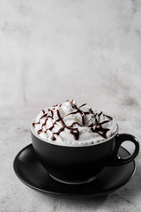Coffe with whipped cream and chocolate topping. Iced frappuccino in dark cup isolated on bright marble background. Overhead view, copy space. Advertising for cafe menu. . Vertical photo.