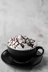 Coffe with whipped cream and chocolate topping. Iced frappuccino in dark cup isolated on bright marble background. Overhead view, copy space. Advertising for cafe menu. . Vertical photo.