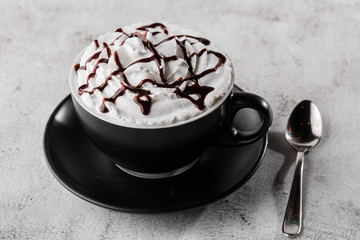Coffe with whipped cream and chocolate topping. Iced frappuccino in dark cup isolated on bright marble background. . Advertising for cafe menu. Coffee shop menu. Horizontal photo.