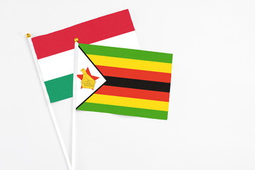 Zimbabwe and Hungary stick flags on white background. High quality fabric, miniature national flag. Peaceful global concept.White floor for copy space.