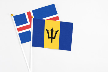 Barbados and Iceland stick flags on white background. High quality fabric, miniature national flag. Peaceful global concept.White floor for copy space.