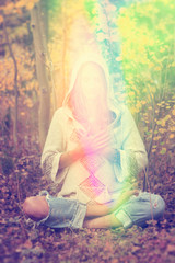 Woman in light drenched enlightenment with hands to her heart in love in nature. 
