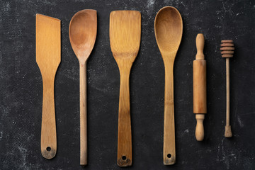 wooden kitchen utensils lying on an old black background