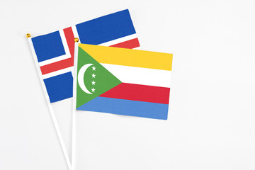 Comoros and Iceland stick flags on white background. High quality fabric, miniature national flag. Peaceful global concept.White floor for copy space.