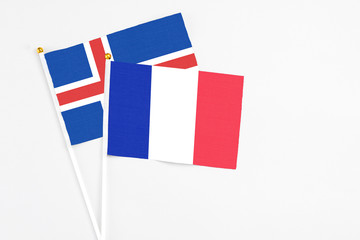 France and Iceland stick flags on white background. High quality fabric, miniature national flag. Peaceful global concept.White floor for copy space.