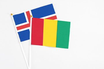Guinea and Iceland stick flags on white background. High quality fabric, miniature national flag. Peaceful global concept.White floor for copy space.