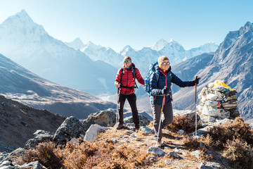 Paar folgt der Everest Base Camp Trekkingroute in der Nähe von Dughla 4620m. Rucksacktouristen, die Rucksäcke tragen und Trekkingstöcke benutzen und den Blick auf das Tal mit dem Ama Dablam 6812m Gipfel genießen