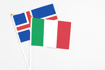 Italy and Iceland stick flags on white background. High quality fabric, miniature national flag. Peaceful global concept.White floor for copy space.