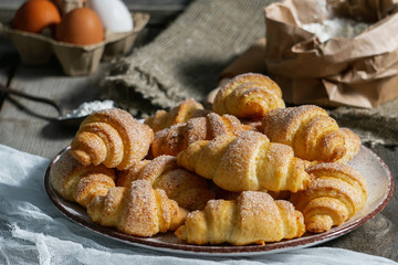 bagels lie in a plate on an old wooden background, next to eggs and flour. bakery products