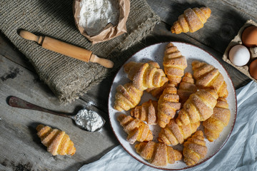 bagels lie in a plate on an old wooden background, next to eggs and flour. bakery products