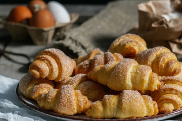 bagels lie in a plate on an old wooden background, next to eggs and flour. bakery products