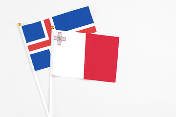 Malta and Iceland stick flags on white background. High quality fabric, miniature national flag. Peaceful global concept.White floor for copy space.
