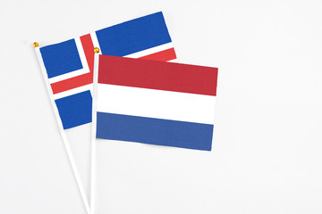 Netherlands and Iceland stick flags on white background. High quality fabric, miniature national flag. Peaceful global concept.White floor for copy space.