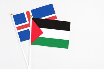 Palestine and Iceland stick flags on white background. High quality fabric, miniature national flag. Peaceful global concept.White floor for copy space.