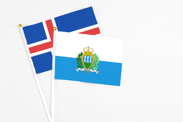San Marino and Iceland stick flags on white background. High quality fabric, miniature national flag. Peaceful global concept.White floor for copy space.