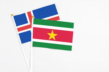 Suriname and Iceland stick flags on white background. High quality fabric, miniature national flag. Peaceful global concept.White floor for copy space.