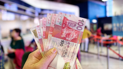 Hand holding Hong Kong dollar (HKD) billnotes with blur exchange waiting line background.