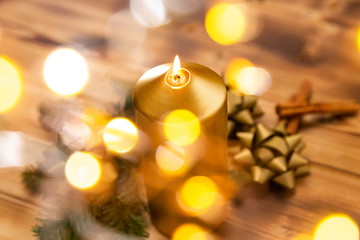 Arrangement aus einer Kerze und Schleifen auf einem Holzhintergrund zur Weihnachtszeit