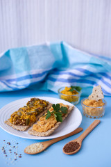 Crackers with chickpea paste on blue background. Sandwiches with hummus. Vegetarian food