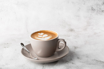 White cup of hot latte coffee with beautiful milk foam latte art texture isolated on bright marble background. Overhead view, copy space. Advertising for cafe menu. Coffee shop menu. Horizontal photo.