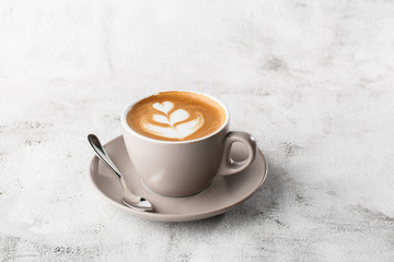 White cup of hot latte coffee with beautiful milk foam latte art texture isolated on bright marble background. Overhead view, copy space. Advertising for cafe menu. Coffee shop menu. Horizontal photo.