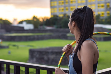 Young woman walks with hula hoop on the street 