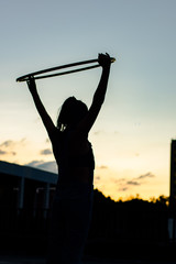 Woman silhouette performs  with hula hoop at sunset 