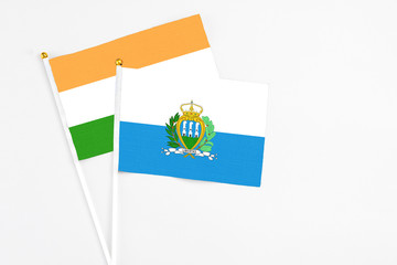 San Marino and India stick flags on white background. High quality fabric, miniature national flag. Peaceful global concept.White floor for copy space.