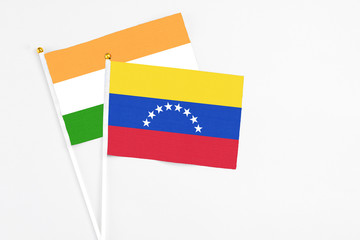 Venezuela and India stick flags on white background. High quality fabric, miniature national flag. Peaceful global concept.White floor for copy space.