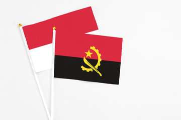Angola and Indonesia stick flags on white background. High quality fabric, miniature national flag. Peaceful global concept.White floor for copy space.