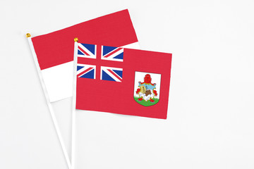 Fototapeta premium Bermuda and Indonesia stick flags on white background. High quality fabric, miniature national flag. Peaceful global concept.White floor for copy space.